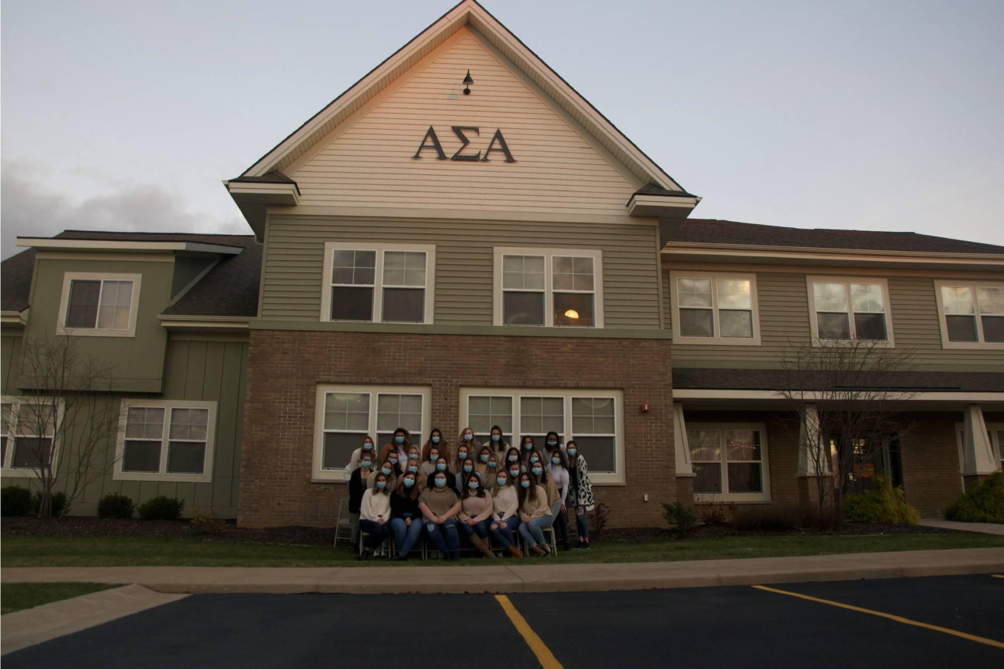 Alpha Sigma Alpha members posing together in masks in front of their house.